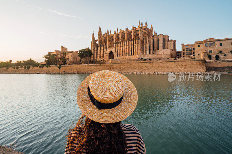 日落时分，一名戴草帽的女子正在欣赏圣塔大教堂María de Palma de Mallorca